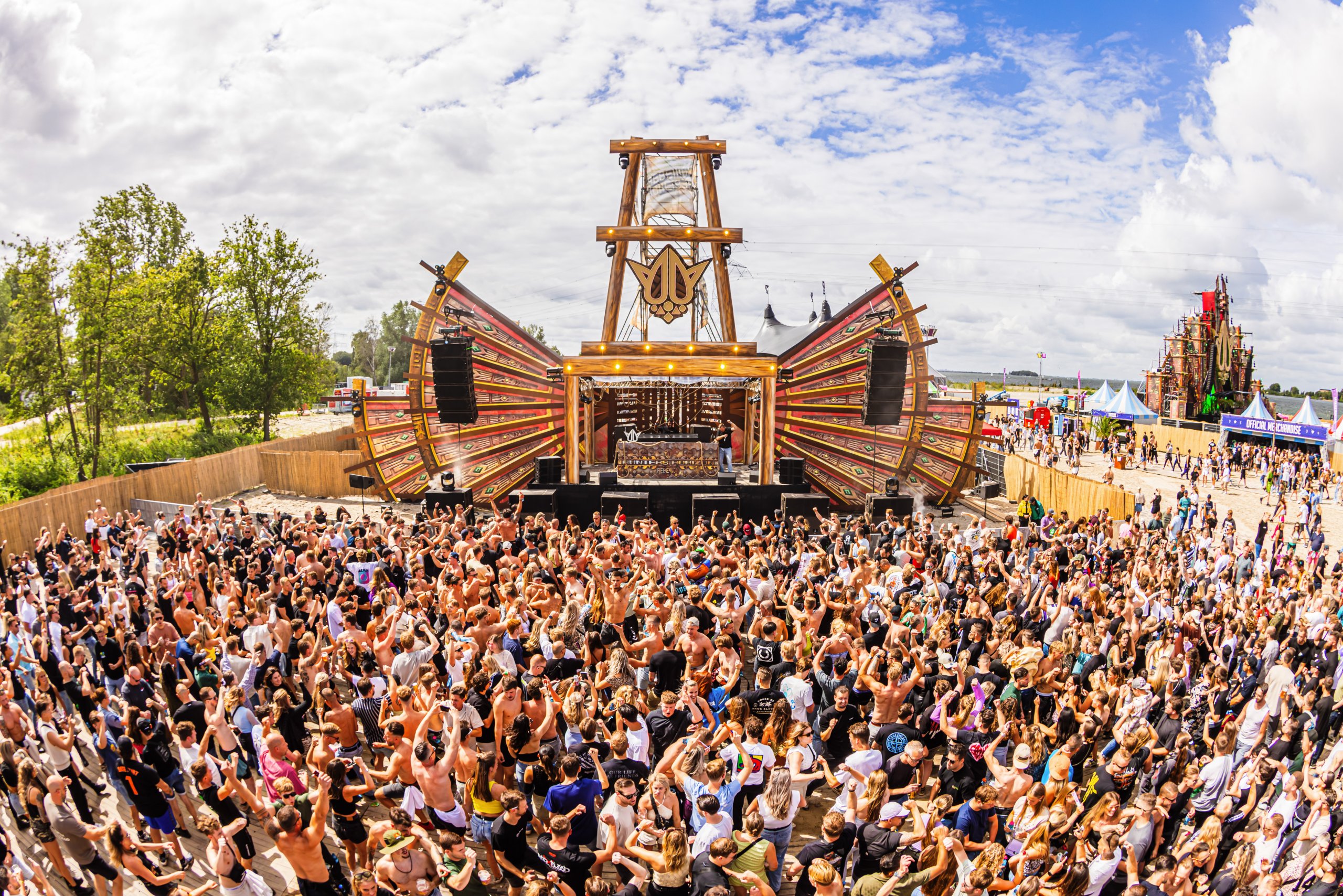 Outdoor festival crowd at wooden stage of REBELLION Outdoor Festival.