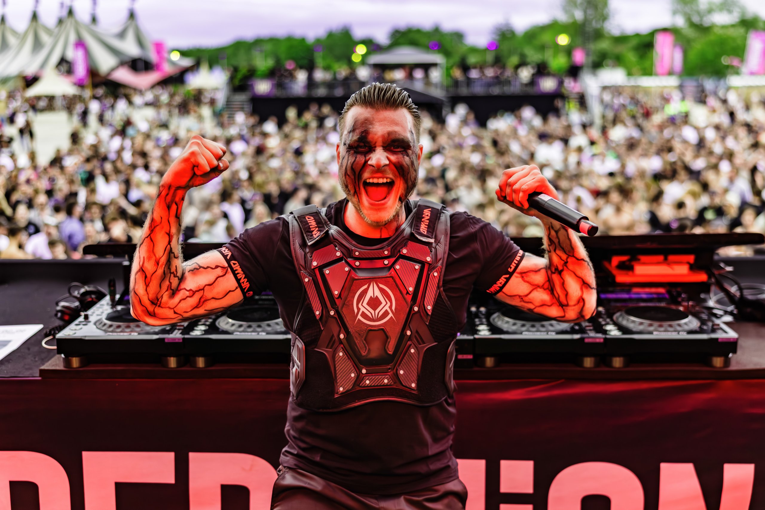 Performer with body paint raises arms in front of the crowd at REBELLION Outdoor Festival.