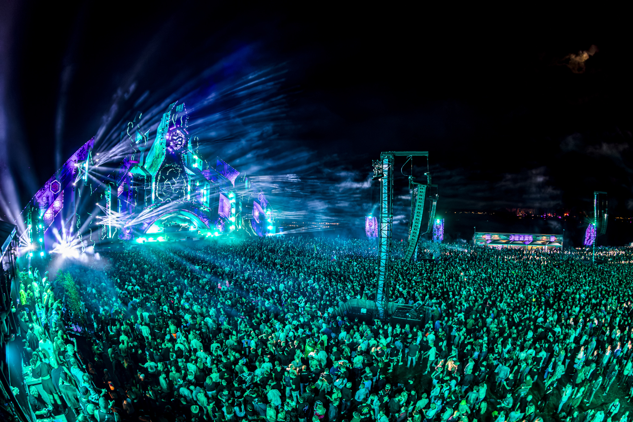 Teal lasers sweep across the crowd at night at Decibel Outdoor Festival 2026