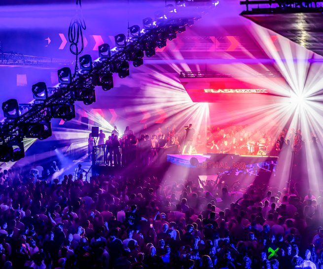Bright beams and purple light over the dancefloor at FLASHBACK 2026