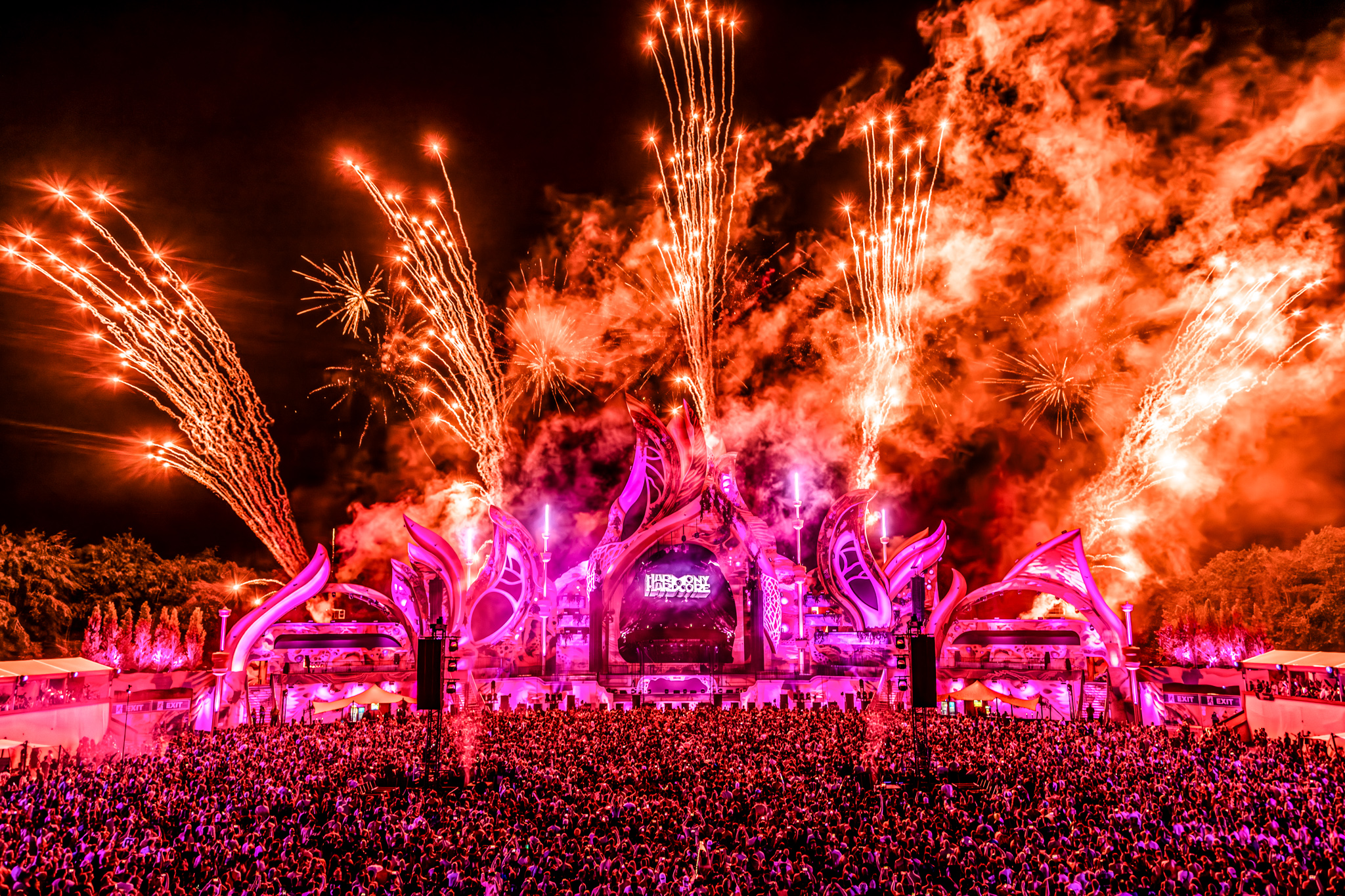 Orange pyro and smoke over the pink-lit mainstage at Harmony of Hardcore 2026