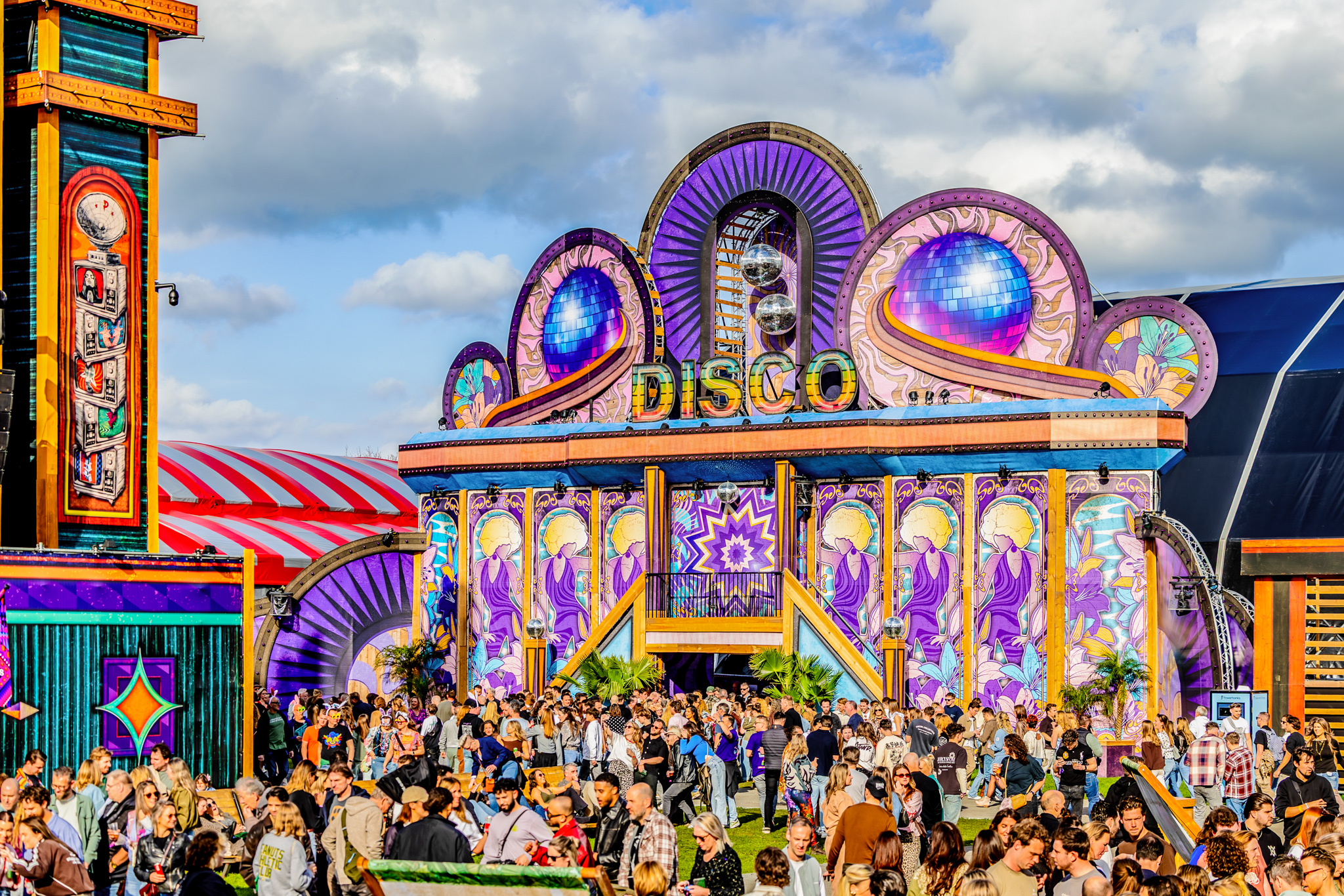 Colourful Disco stage with mirror balls and a busy crowd at Paaspop 2026