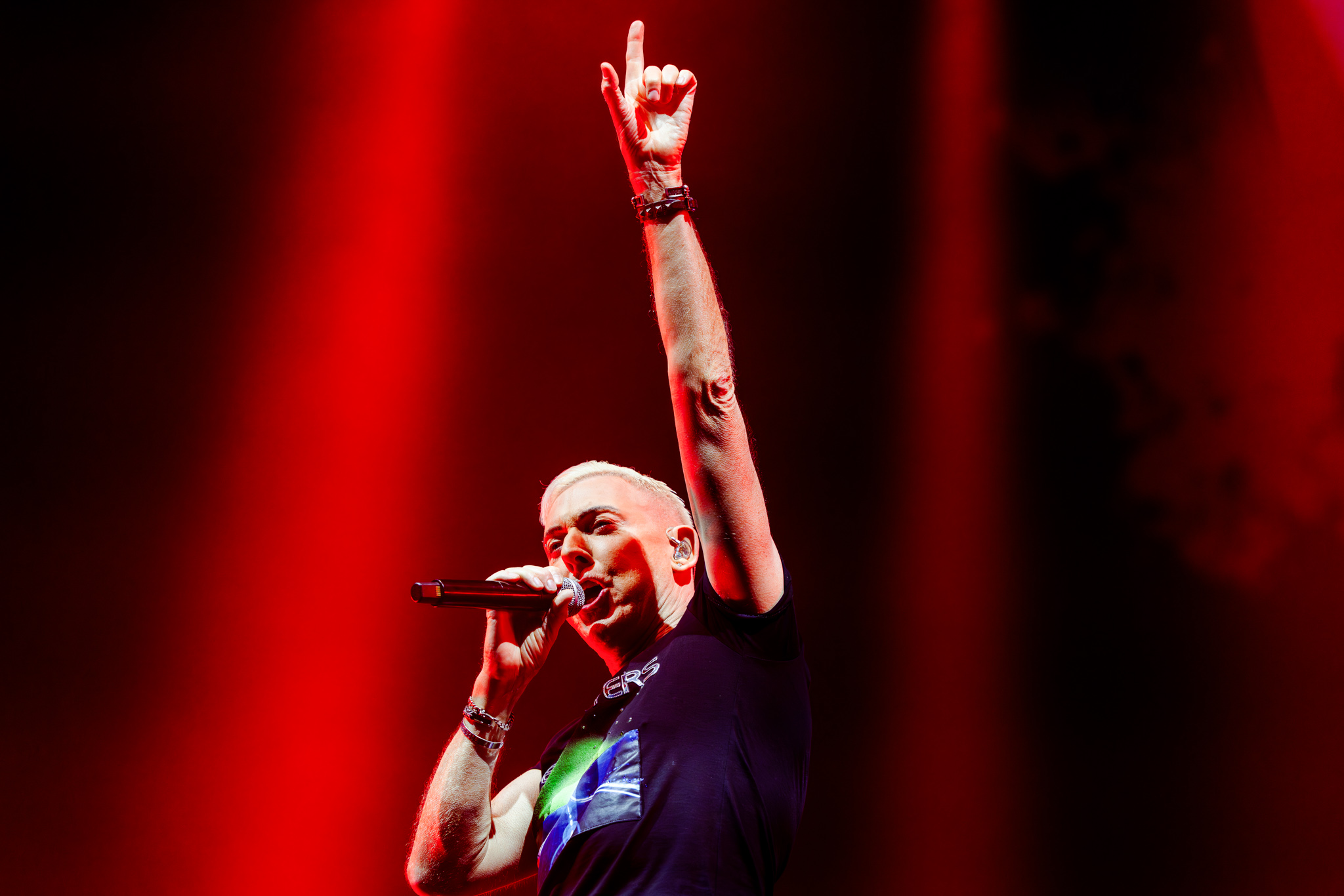 Frontman pointing up with his microphone in red light during the Scooter show at Paaspop 2026