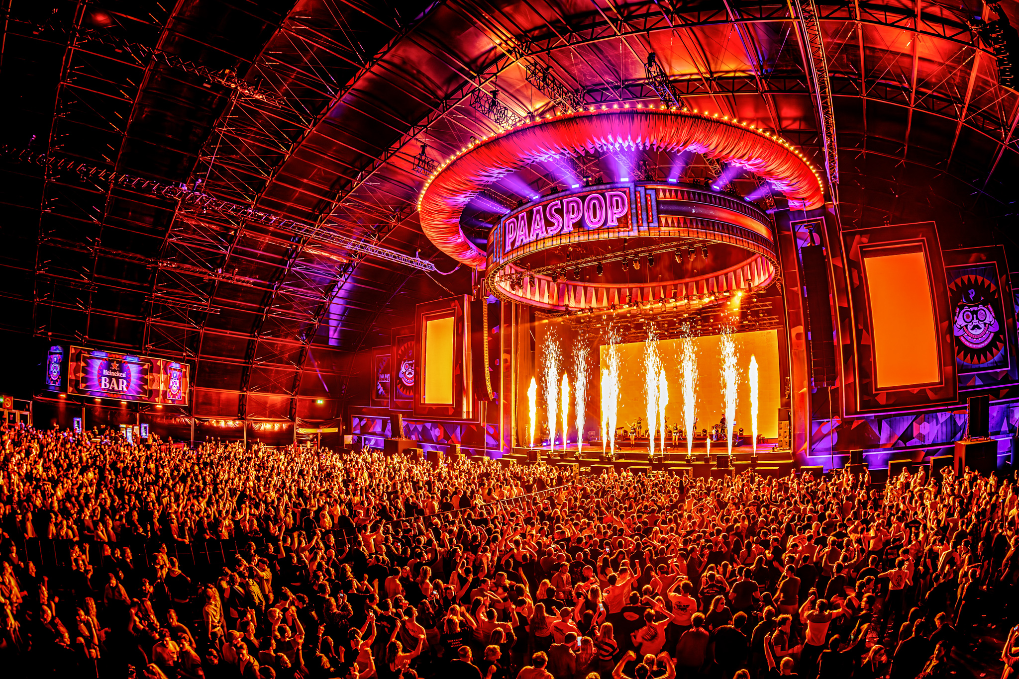 Packed main hall with flames on stage under the Paaspop sign at Paaspop 2026