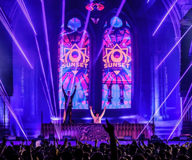 DJs on stage in front of stained-glass Sunset screens at Sunset Festival 2026